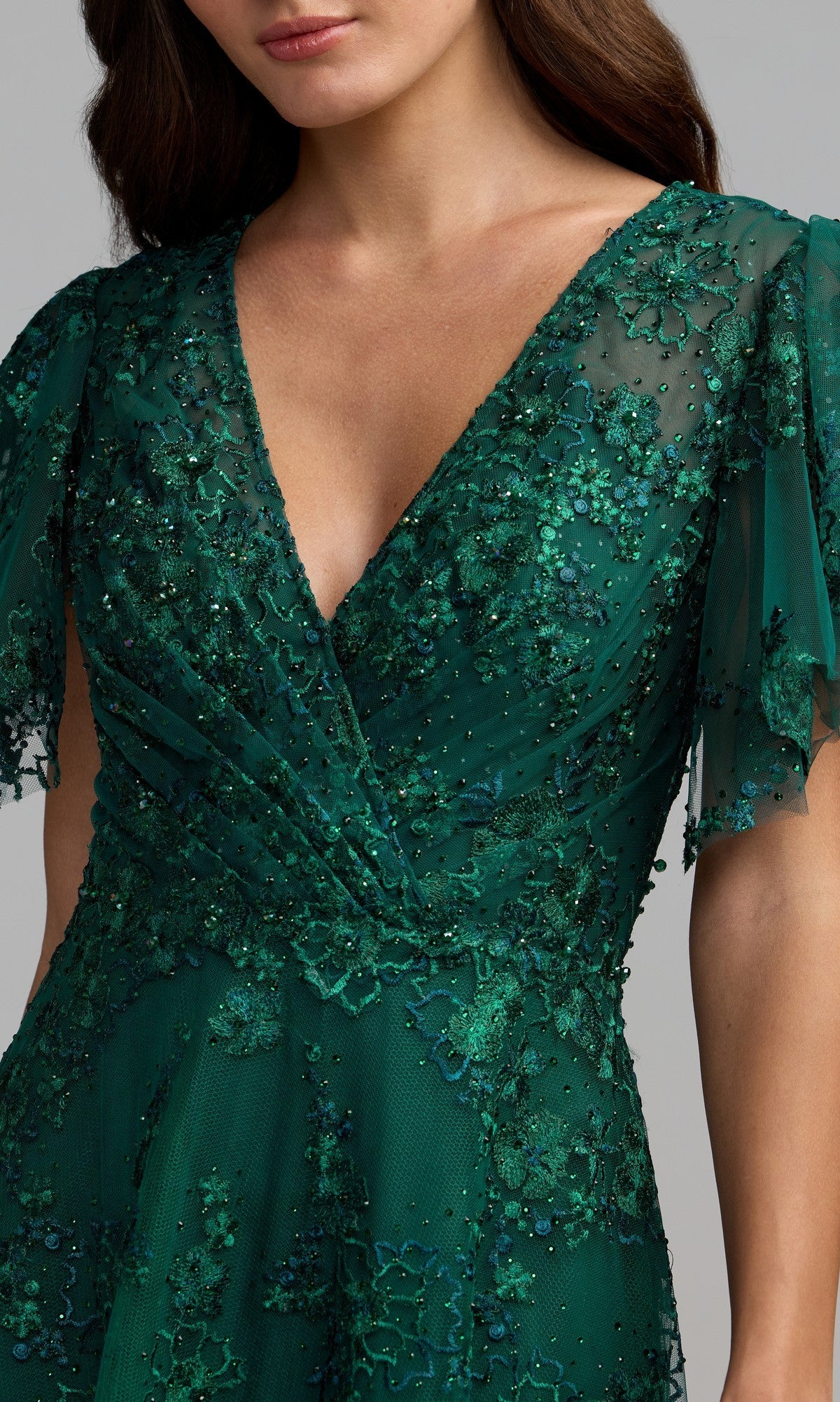A person wearing the Short Sleeve Mauve Formal Dress: Mac Duggal 20486, featuring a v-neckline, intricate beadwork, and floral lace details on sheer mauve fabric.